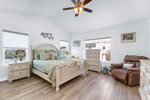 Bedroom featuring multiple windows, lofted ceiling, ceiling fan, and light wood-type flooring