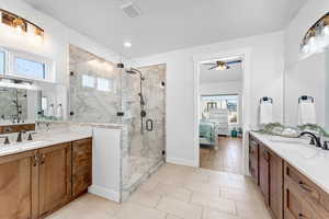 Bathroom featuring vanity, a shower with shower door, and ceiling fan