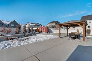 Snow covered patio with a gazebo and a storage shed