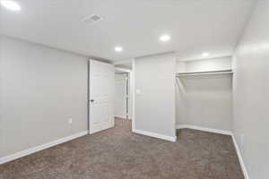 Unfurnished bedroom featuring dark colored carpet and a closet