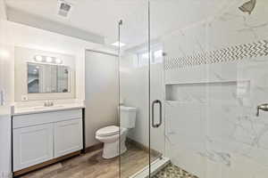 Bathroom featuring an enclosed shower, vanity, wood-type flooring, and toilet