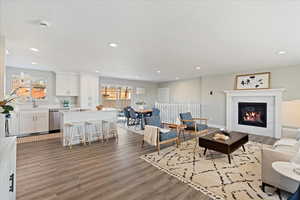 Living room with a high end fireplace, sink, hardwood / wood-style floors, and a textured ceiling