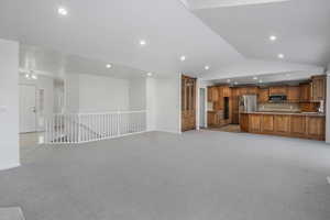 Unfurnished living room featuring light carpet and high vaulted ceiling