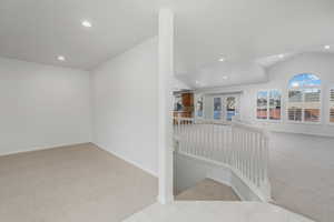 Hallway featuring lofted ceiling and light colored carpet