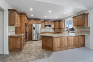 Kitchen featuring appliances with stainless steel finishes, kitchen peninsula, and decorative backsplash