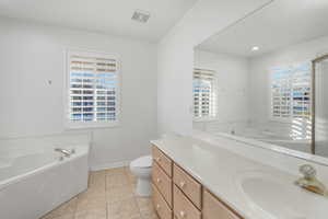 Bathroom featuring vanity, a bath, tile patterned flooring, and a wealth of natural light