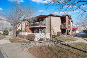 View of side of property with a balcony and a lawn