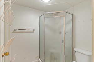 Bathroom featuring an enclosed shower, a textured ceiling, and toilet