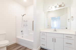 Full bathroom featuring wood-type flooring, vanity, washtub / shower combination, and toilet