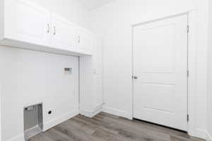 Laundry room with electric dryer hookup, hookup for a washing machine, light hardwood / wood-style floors, and cabinets