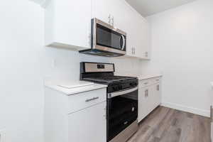 Kitchen featuring appliances with stainless steel finishes, light hardwood / wood-style floors, and white cabinets