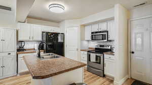 Kitchen with included stainless steel appliances, white cabinetry, and island