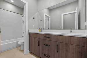 Full bathroom featuring tile patterned flooring, vanity, tiled shower / bath, and toilet