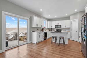 Kitchen featuring sink, a breakfast bar area, appliances with stainless steel finishes, white cabinets, and a kitchen island