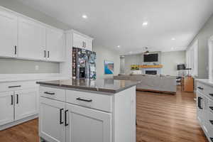 Kitchen with hardwood / wood-style flooring, white cabinetry, a center island, and stainless steel fridge with ice dispenser