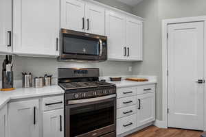 Kitchen with light hardwood / wood-style flooring, white cabinets, and appliances with stainless steel finishes