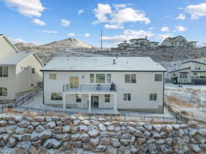 Snow covered house featuring a mountain view and a balcony