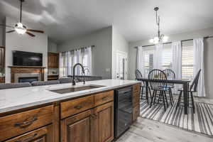 Kitchen featuring vaulted ceiling, a wealth of natural light, dishwasher, sink, and light stone counters