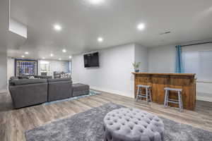 Living room with bar area and light wood-type flooring