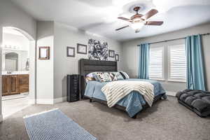 Carpeted bedroom featuring ceiling fan, sink, and ensuite bath