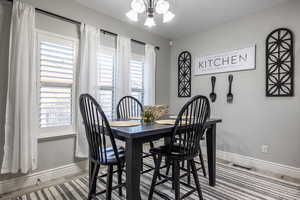 Dining room featuring a healthy amount of sunlight, hardwood / wood-style floors, and a notable chandelier