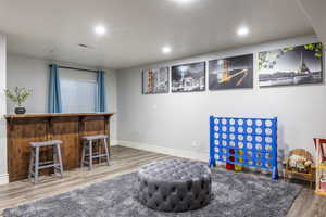 Rec room with hardwood / wood-style floors and bar area