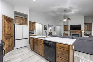 Kitchen featuring dishwasher, an island with sink, sink, white refrigerator, and light wood-type flooring