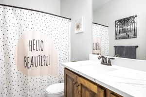 Bathroom with vanity, a shower with curtain, and toilet