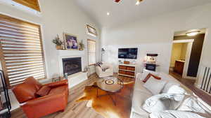 Living room featuring ceiling fan, high vaulted ceiling, and light hardwood / wood-style flooring