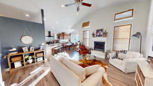 Living room with ceiling fan, high vaulted ceiling, sink, and light hardwood / wood-style floors