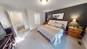 Carpeted bedroom featuring ensuite bathroom