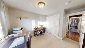 Home office featuring light colored carpet and a textured ceiling