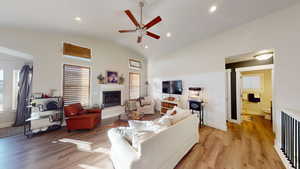 Living room featuring ceiling fan, high vaulted ceiling, radiator heating unit, and light wood-type flooring