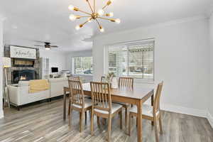 Dining area with ornamental molding, laminate flooring, and a notable chandelier.