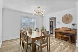 Dining room featuring crown molding, laminate flooring, and a chandelier.