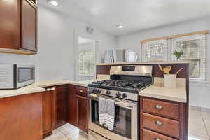 Kitchen featuring light tile patterned flooring, appliances with stainless steel finishes, and kitchen peninsula