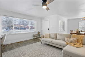 Living room with crown molding, plenty of natural light, laminate / wood-style floors, and ceiling fan with notable chandelier