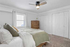 Bedroom featuring multiple closets, ceiling fan, a wall mounted AC, and carpet