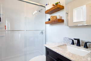 Bathroom with vanity, toilet, and a shower with shower door