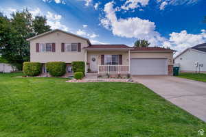 Tri-level home with a garage, a porch, and a front lawn