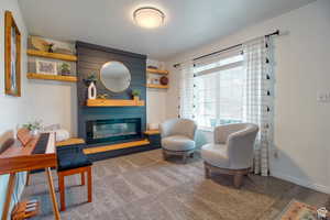 Living area featuring a large fireplace, carpet, and a textured ceiling