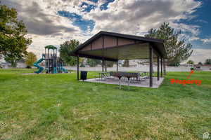 View of property's community featuring a yard, a playground, and a patio area