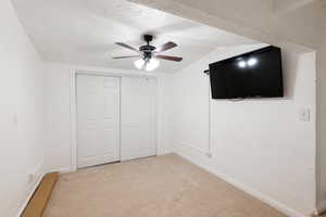 Unfurnished bedroom featuring light colored carpet, a closet, and ceiling fan