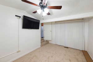 Interior space featuring lofted ceiling, light colored carpet, and ceiling fan