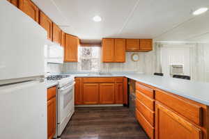 Kitchen with dark hardwood / wood-style flooring, sink, and white appliances