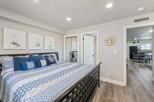 Bedroom with black fridge, a textured ceiling, a closet, and hardwood / wood-style flooring