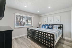 Bedroom with hardwood / wood-style flooring and a textured ceiling