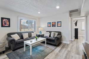 Living room featuring a textured ceiling and light wood-type flooring