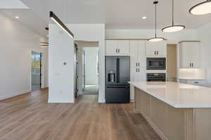 Kitchen featuring white cabinetry, hanging light fixtures, black appliances, and a kitchen island