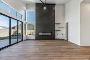 Unfurnished living room featuring a large fireplace, a high ceiling, and light wood-type flooring